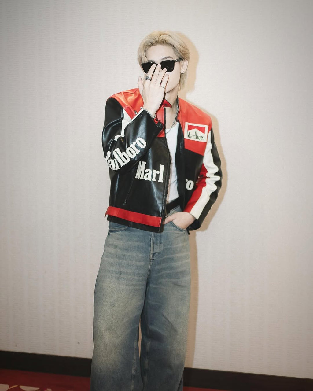 Person wearing a LZRUS Black Marlboro Leather Jacket – Vintage Racing Streetwear Style and sunglasses against a plain background