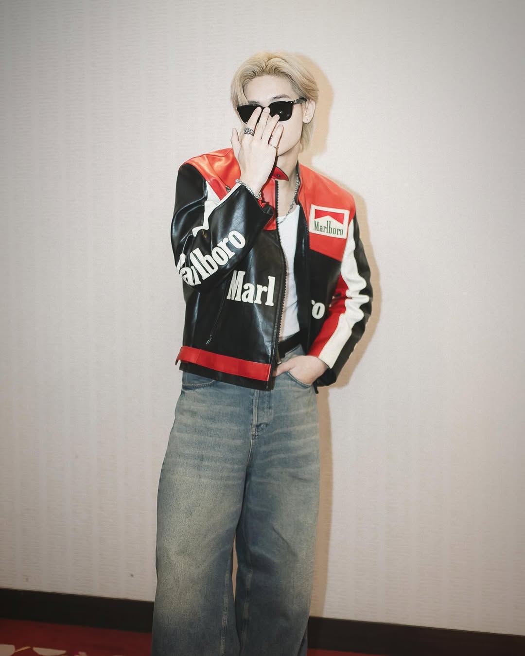 Person wearing a LZRUS Black Marlboro Leather Jacket – Vintage Racing Streetwear Style and sunglasses against a plain background