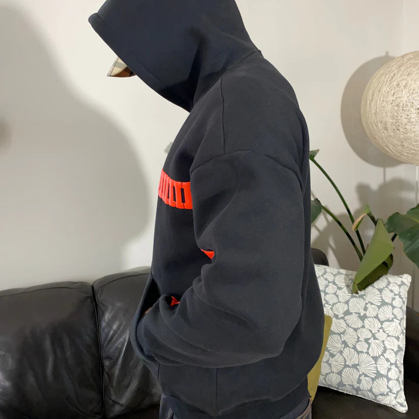 Person wearing a Valentine gift love hoodie – LZRUS streetwear fashion with a red stripe in a room with a couch and plant.