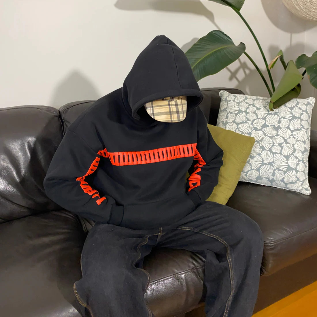 Person wearing a Romantic couple hoodie with oversized streetwear fit with red accents sitting on a brown leather couch.