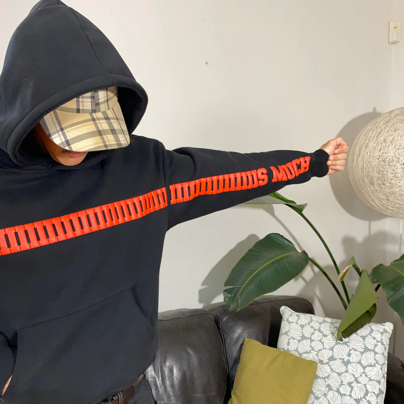Oversized statement hoodie for couples – I Love You This Much design Person wearing a black hoodie with red text, standing indoors with a plant and sofa in the background.