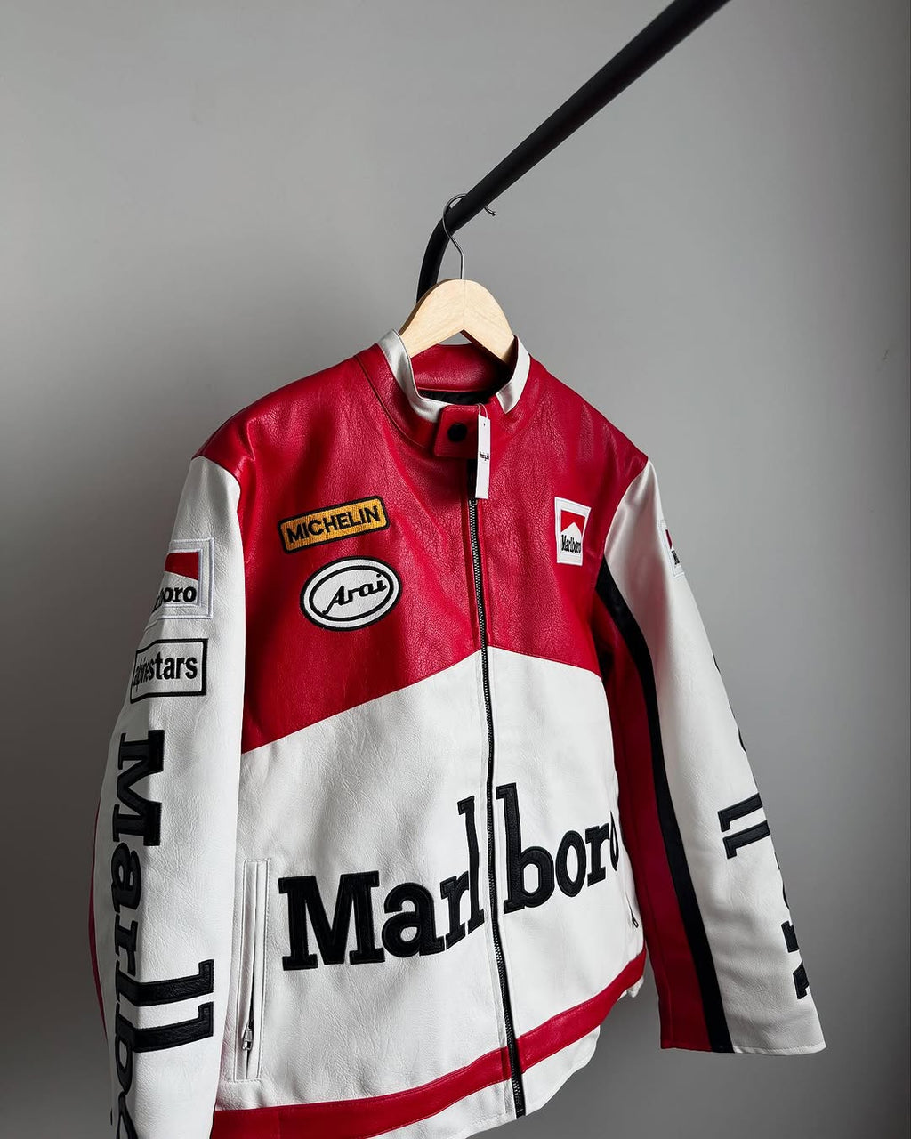 LZRUS Marlboro Racing leather jacket hanging on wooden hanger showcasing front racing design and logos