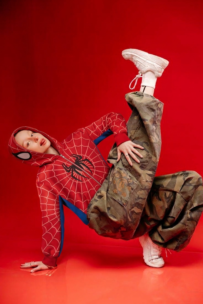 Oversized spider hoodie photographed mid movement in a floor pose, showing the drape through the shoulders and hood